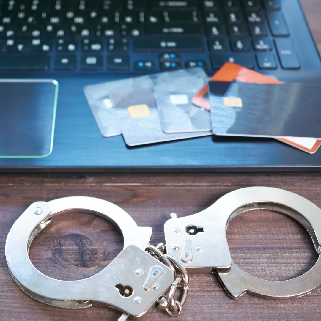 Image shows credit cards laid out on laptop. Handcuffs in front of laptop to show credit card fraud